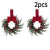 Two artificial Christmas wreaths featuring green foliage, red berries, and a large red velvet bow.