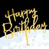 Gold acrylic letters spelling happy birthday on a white cake with white decorations