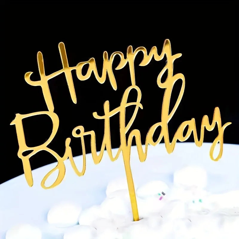 Gold acrylic letters spelling happy birthday on a white cake with white decorations