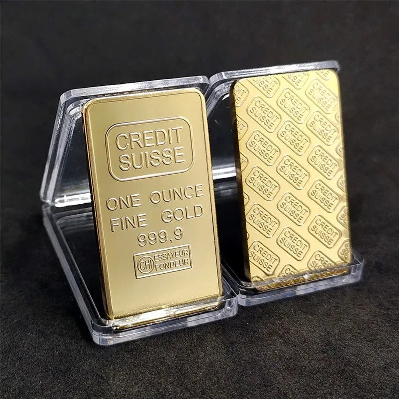 A clear plastic case holds two gold plated bullion ingots labeled Credit Suisse with 999.9 purity.