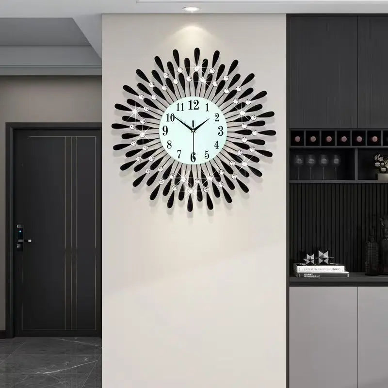 A modern minimalist metal wall clock with a white face and black spokes is mounted on a light gray wall.
