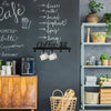 A black chalkboard wall displays a list of coffee terms and a wooden cabinet next to a metal shelf unit.