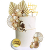 A white cake decorated with gold and champagne-colored spherical toppers and a gold birthday banner.