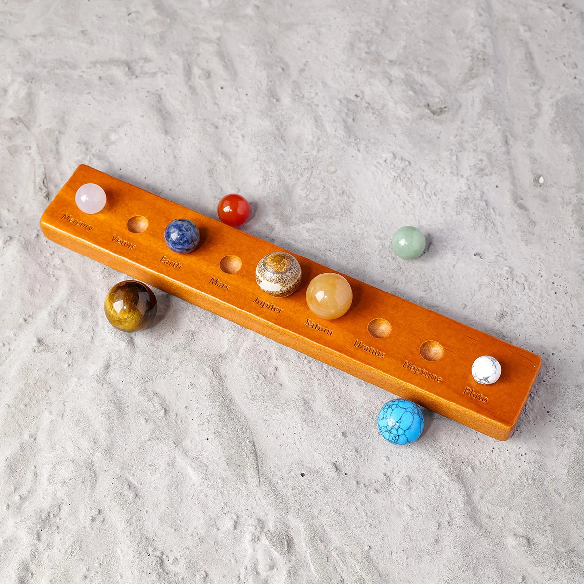 A wooden set of natural crystal planet balls representing the solar system, arranged in a linear display.