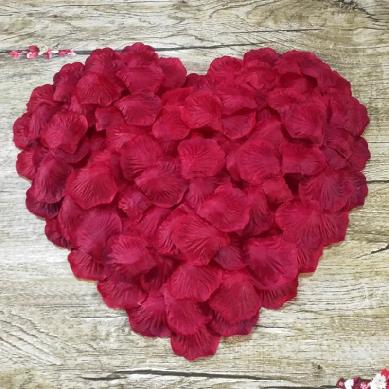 A heart-shaped arrangement of deep red silk rose petals for weddings and events.