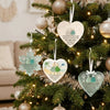 A handcrafted acrylic friendship snowflake Christmas pendant hanging on a decorated green Christmas tree.