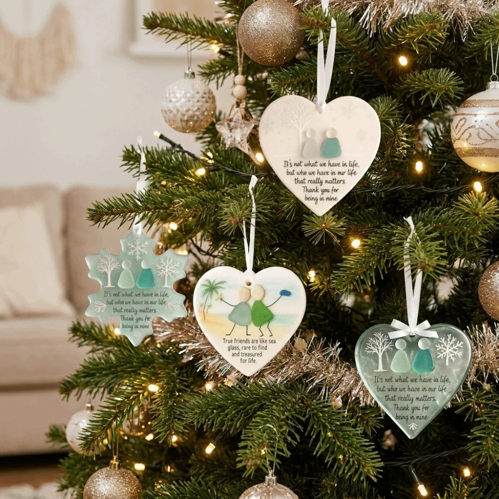 A handcrafted acrylic friendship snowflake Christmas pendant hanging on a decorated green Christmas tree.