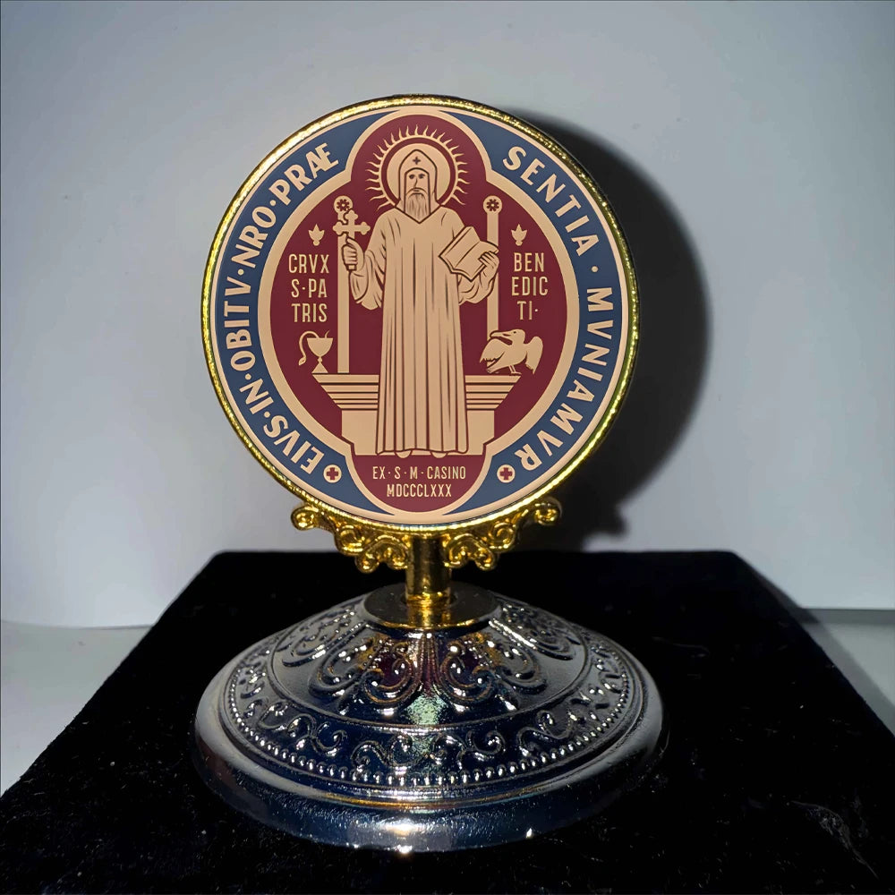 A round gold-rimmed ornament featuring a religious design with Latin text and a figure in a robe.