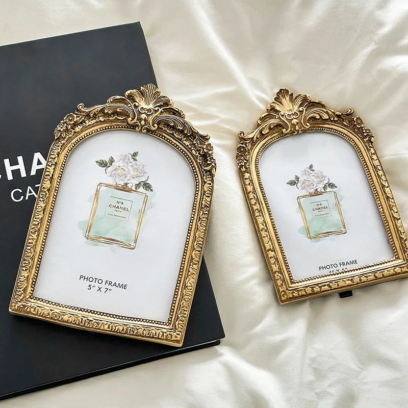 A gold-framed vintage resin photo frame with a floral design displayed on a dark background.