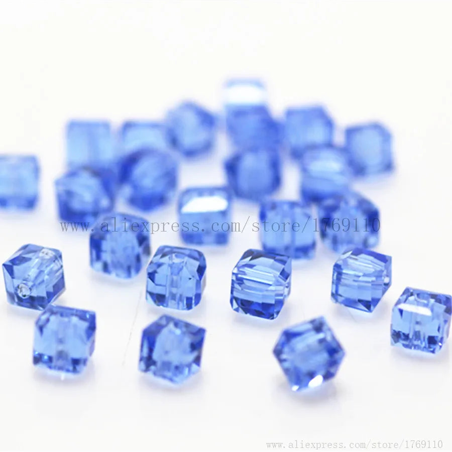 A pile of small, square cut blue glass crystal beads for jewelry making.