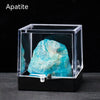 A clear box displaying a vibrant blue apatite crystal rough stone specimen.