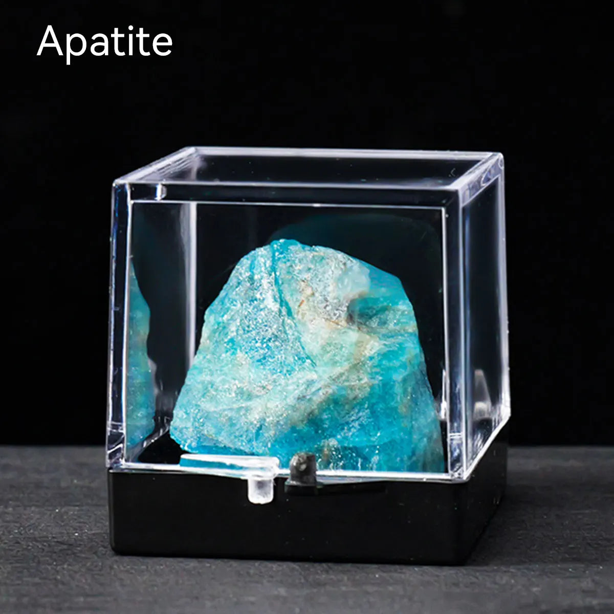 A clear box displaying a vibrant blue apatite crystal rough stone specimen.