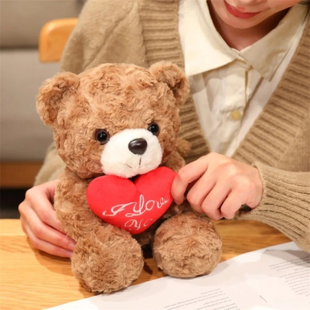 A child holds a red rose bear plush toy against a light background.