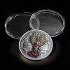 A commemorative coin of Saint Michael the Archangel resting on a black surface with two clear circular containers.