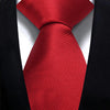 A red silk necktie tied in a knot against a black suit jacket.
