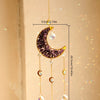 A hanging crystal dreamcatcher featuring a purple crescent moon and dangling clear crystals.