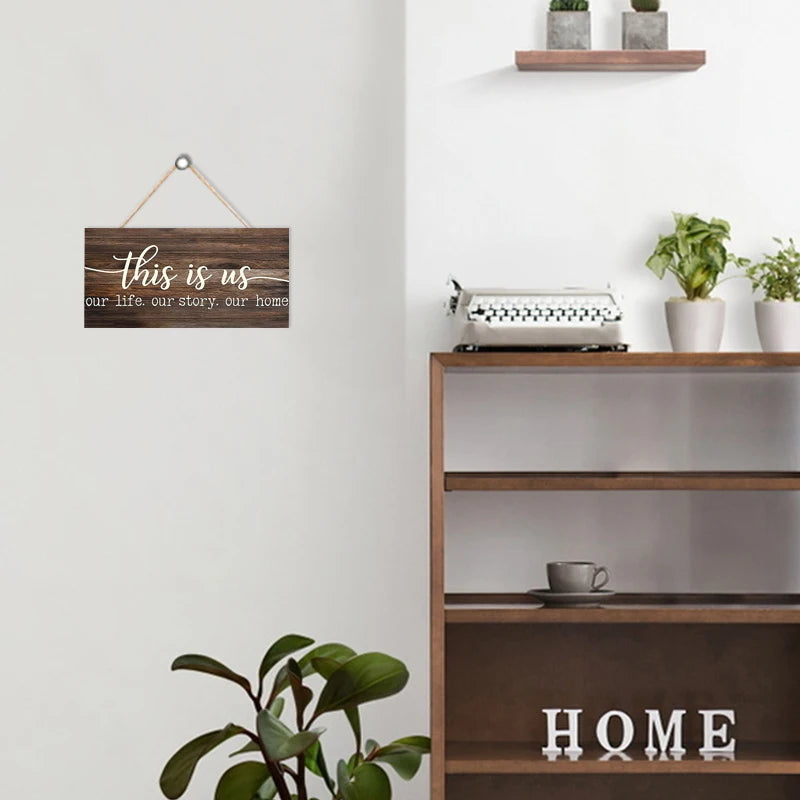Rustic wooden wall sign with the text This is us our life our story our home mounted on a white wall