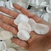 A hand holds a cluster of white silk rose petals for weddings and events.