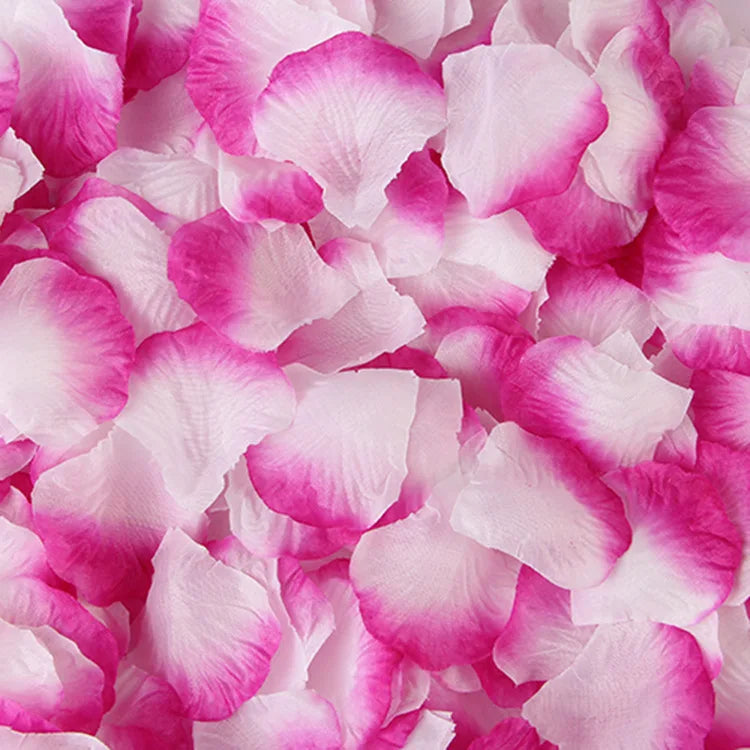 Pink and magenta artificial silk rose petals scattered on a white background.
