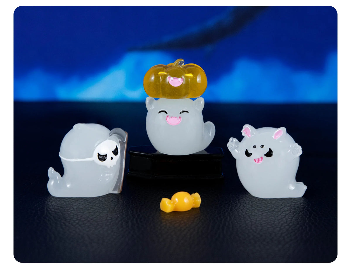 A set of seven cute luminous ghost resin ornaments, including a pumpkin and three white ghostly figures, displayed on a dark 
