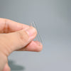 A hand holds a clear, thin glass tube or pipette against a light gray background.