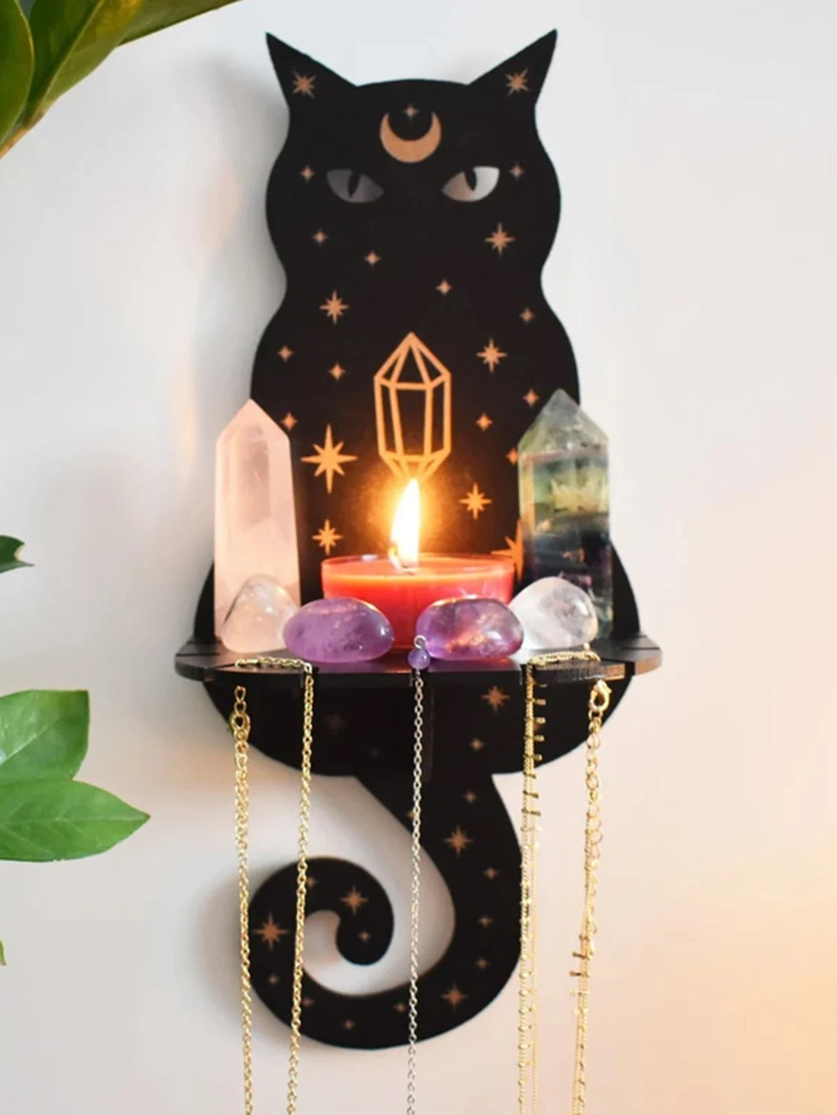 A black cat silhouette with a crescent moon, holding a lit candle and various crystals on a floating shelf.