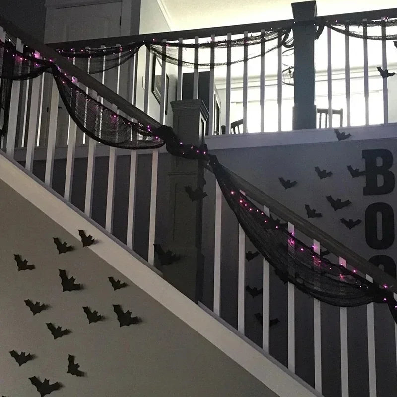Black gauze netting draped across a balcony railing with small black bats decorating the scene.