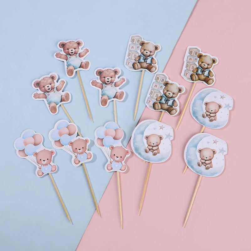 A collection of cute cartoon bear cupcake toppers on wooden sticks in pastel pink and blue colors.