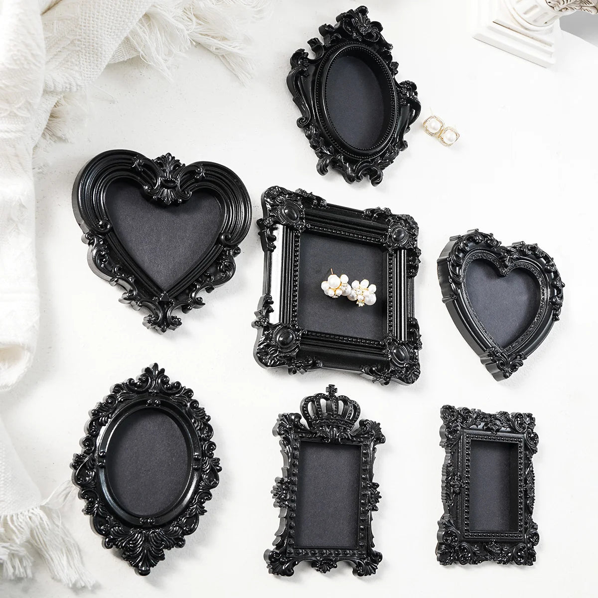 A collection of black resin wall decor pendants in various heart and rectangular shapes with ornate edges.