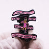 A black enamel pin badge featuring a stylized illustration of a person and text that reads I'm no hero I put my bra on one bo