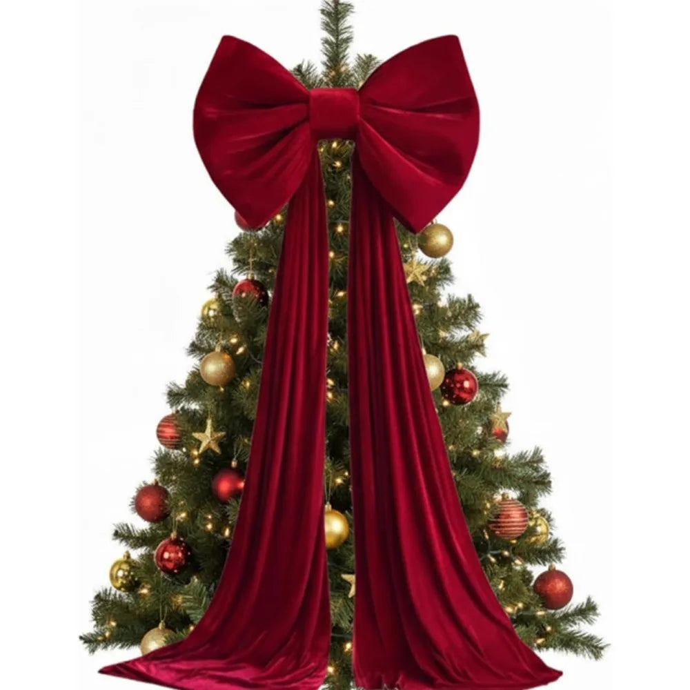 A velvet Christmas tree bow with long draping red tails decorating a green fir tree.