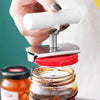 A hand is using an adjustable stainless steel jar opener to open a glass jar of preserves.
