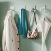 Stainless steel self-adhesive wall hooks hanging a light beige coat and a teal towel on a green wall.
