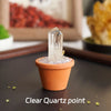 A clear quartz point crystal is displayed in an orange pot on a dark surface.