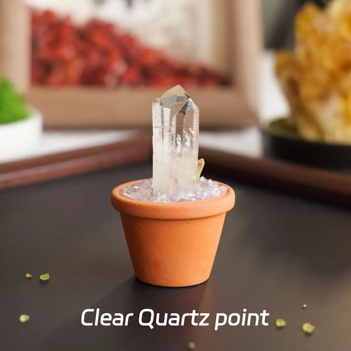 A clear quartz point crystal is displayed in an orange pot on a dark surface.