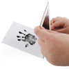 A hand holds a white card featuring a black ink pet paw print, next to a triangular wooden piece.