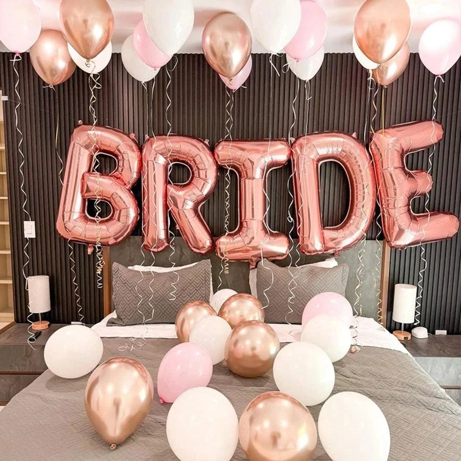 A pink and gold foil balloon arch spelling the word BRIDE decorated with white and pink balloons.