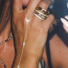 A close-up of a hand wearing multiple gold and diamond layering chain bracelets on the wrist.