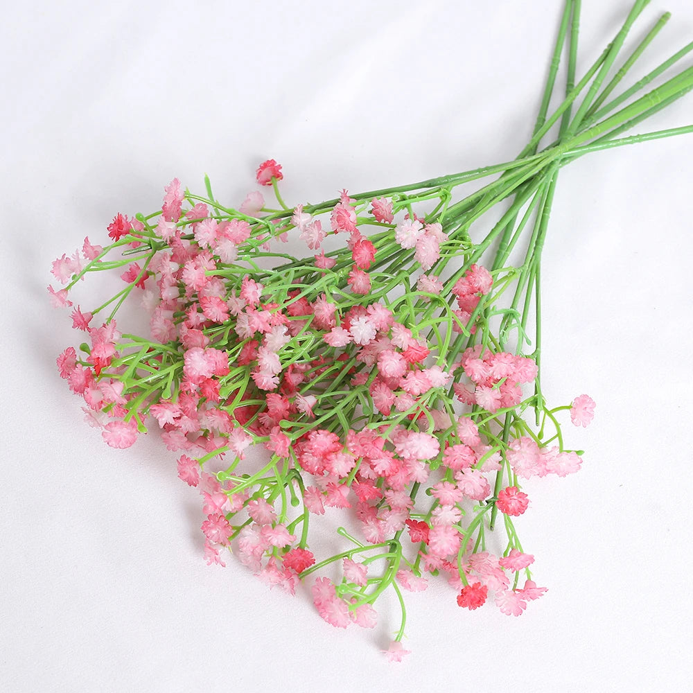 A bunch of pink artificial baby's breath flowers with green stems.