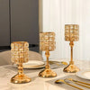 Un juego de candelabros de cristal dorado exhibidos en una mesa de mármol con cubertería y platos.