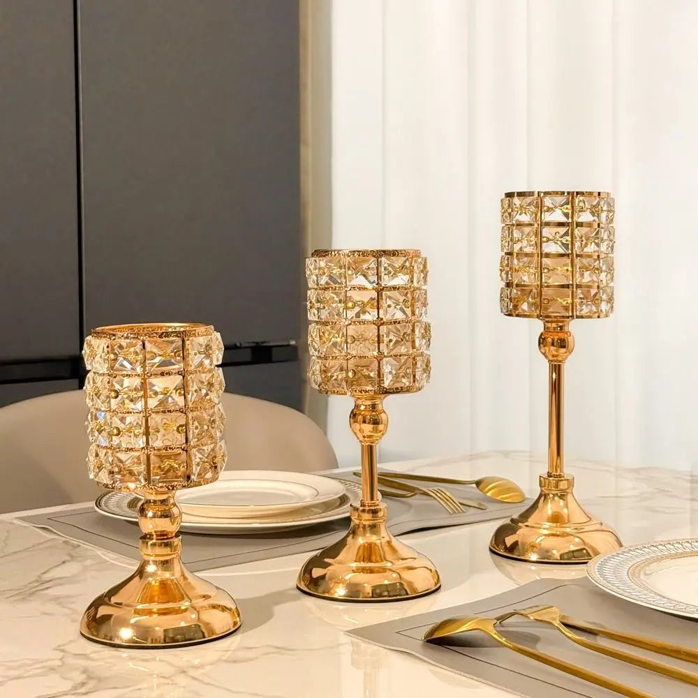 Un juego de candelabros de cristal dorado exhibidos en una mesa de mármol con cubertería y platos.
