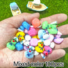A hand holds a mixed color set of 100 mini resin cruise ducks with sunglasses