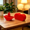 A red heart-shaped novelty desk decor item sits on a wooden table.