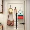 A white door features aluminum wall-mounted hooks displaying a light hat, a dark scarf, and two colored bags.
