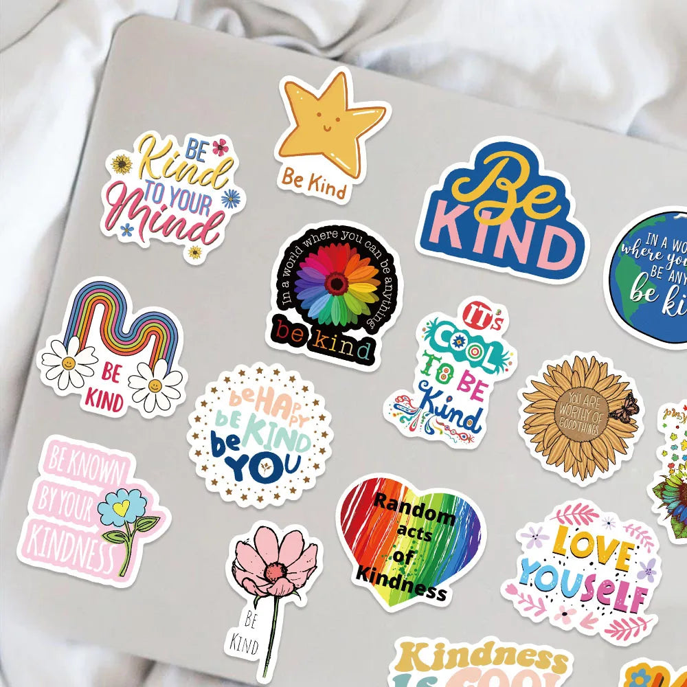 A collection of inspirational motivational stickers featuring words like Be Kind and Love Yourself on a laptop surface.