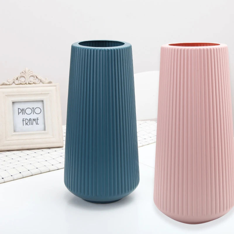 Two tall, ribbed ceramic vases in teal and pink standing on a white surface.