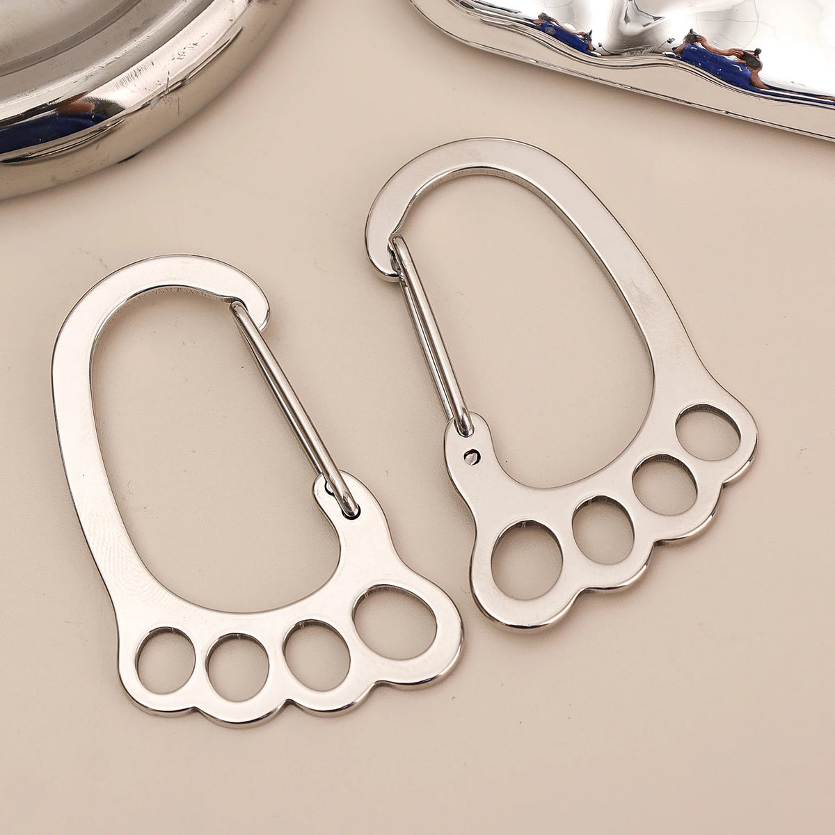 A silver stainless steel keychain with a multi-loop design is shown against a light background.