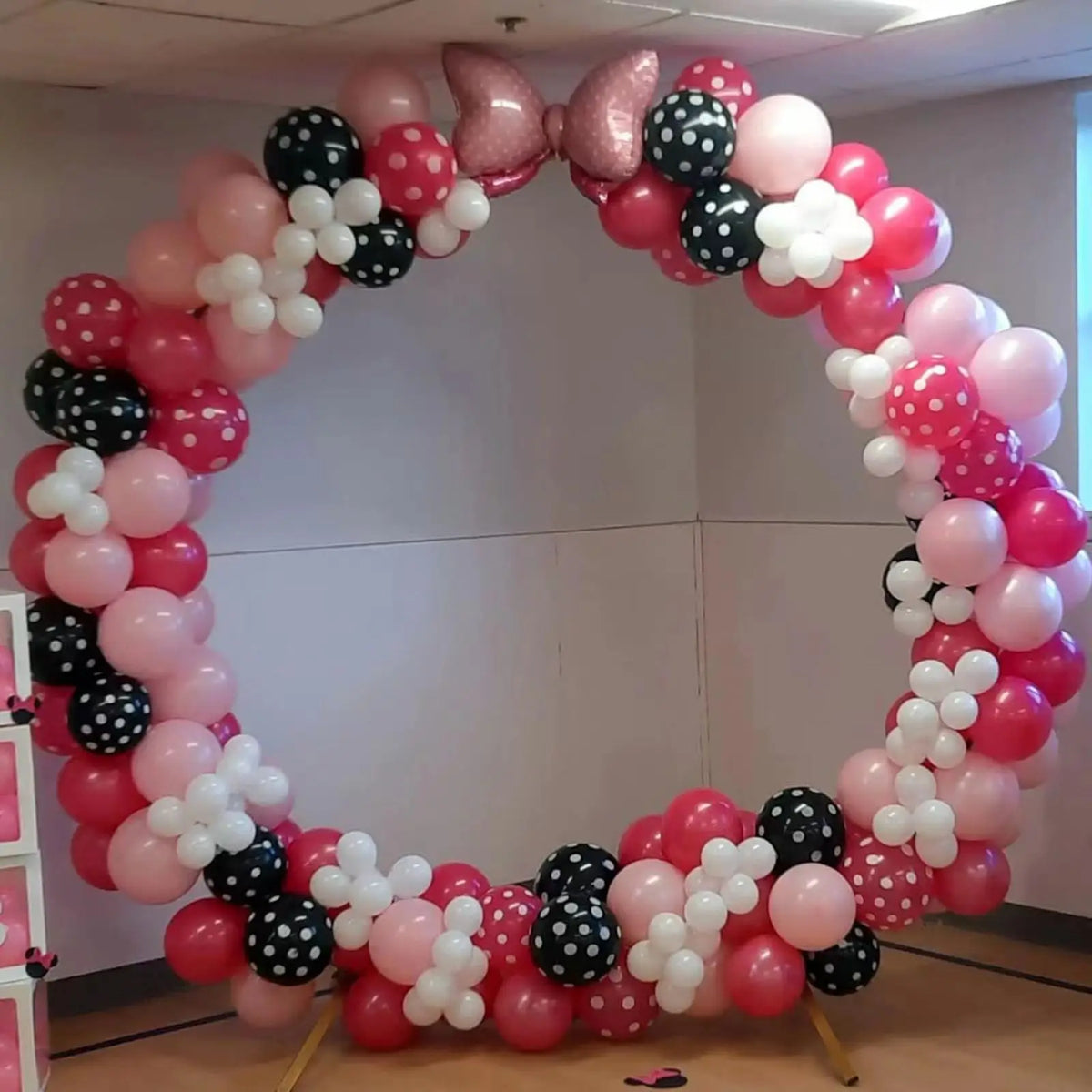 A balloon wreath archway made of pink and white balloons with black accents for parties and celebrations.