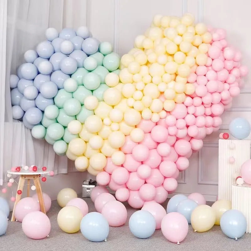 A large balloon bouquet featuring pastel macaron balloons in a rainbow gradient of blue, green, yellow, and pink.