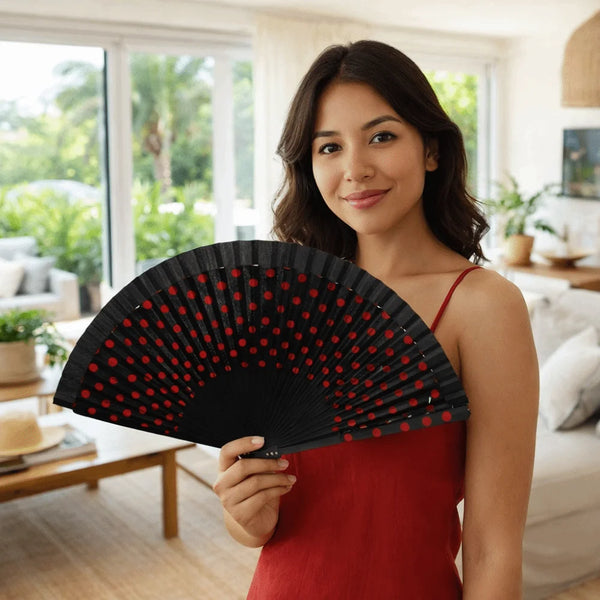A woman holds a black flamenco Spanish folding fan with a wooden handle in a bright indoor setting.